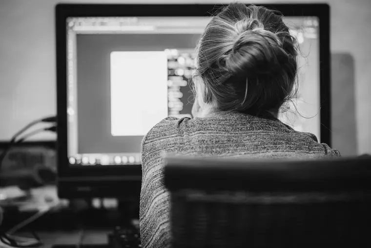 Femme vue de dos, assise devant un écran d’ordinateur dans un bureau