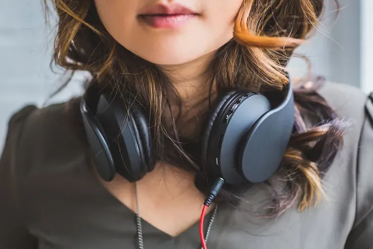 Femme portant un casque audio noir autour du cou, seul le bas du visage est visible
