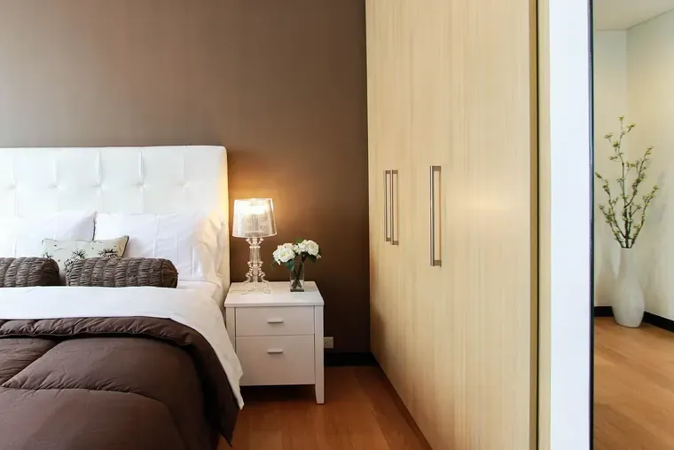 Chambre avec un lit aux draps blancs et une table de chevet éclairée par une lampe