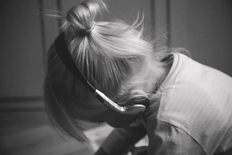 Enfant penché en avant, un casque audio sur la tête, vu de dos et de côté