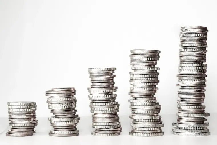 Cinq piles de pièces de monnaie de hauteurs croissantes sur fond blanc